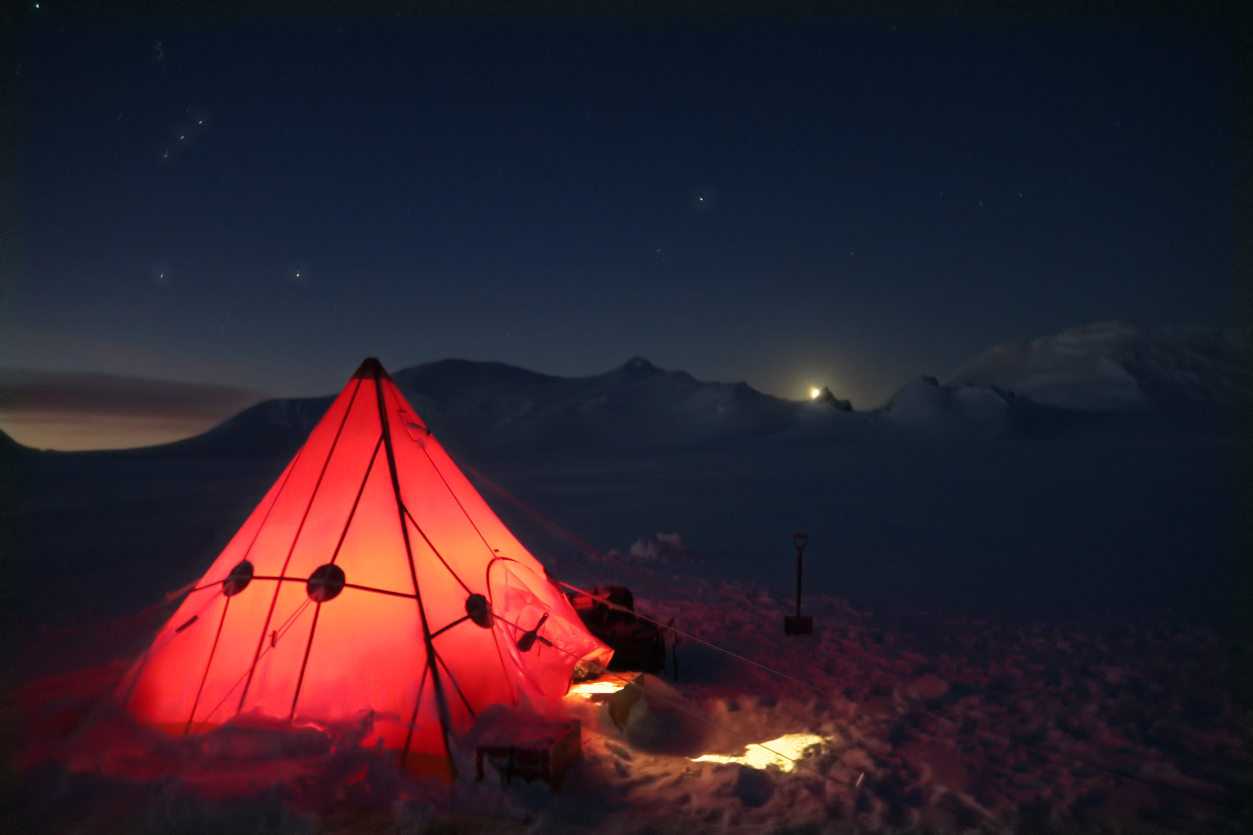 A tent in a dark room with a sunset in the background.