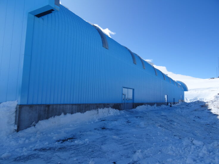 The side of a large blue building in a snowy environment