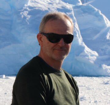 A man wearing sunglasses and standing in front of a mountain