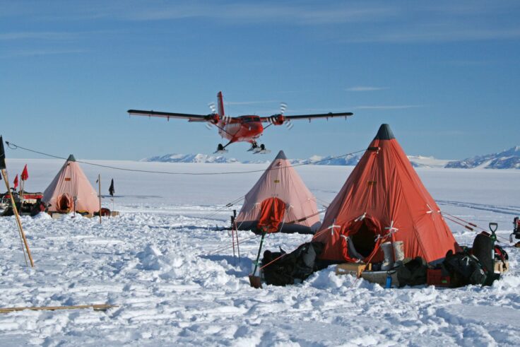 A field camp in Antarctica with twin otter aircraft overhead