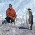 A man sitting next to a penguin in the snow