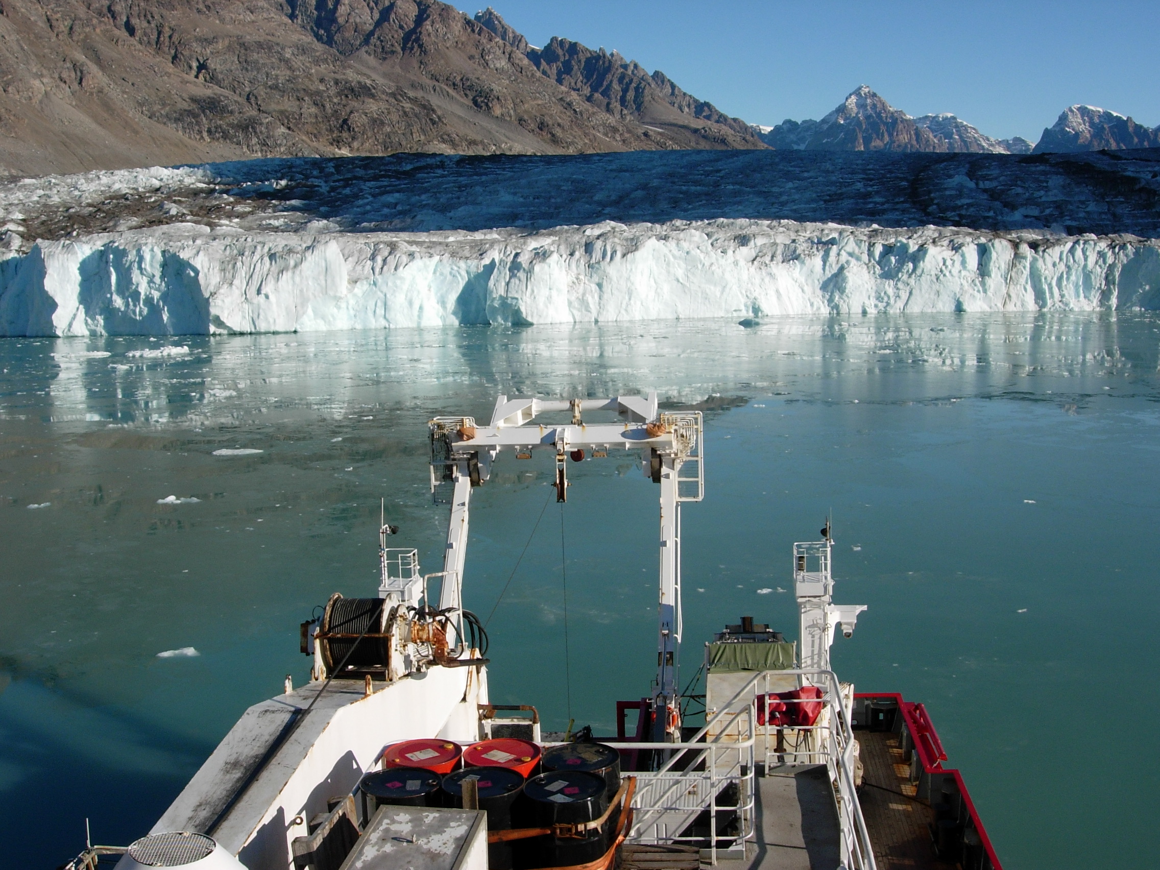 A large ship in a body of water, in front of a glacier