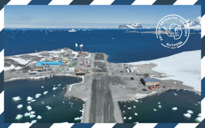 A postcard style image of a runway and a large blue building surrounded by water and snow