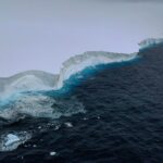 An aerial view of the edge of a large iceberg