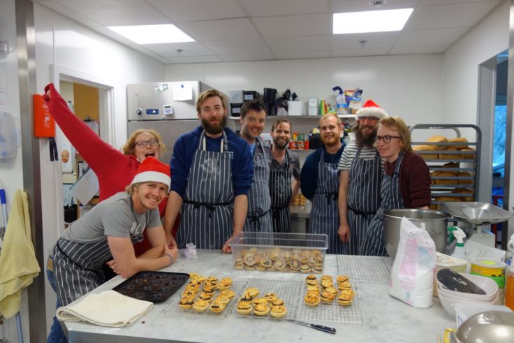 A group of people preparing mince pies in a kitchen