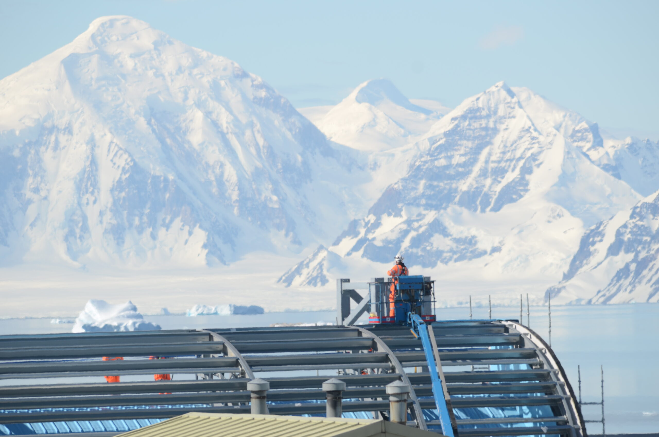 A building being constructed by the side of a snowy mountain