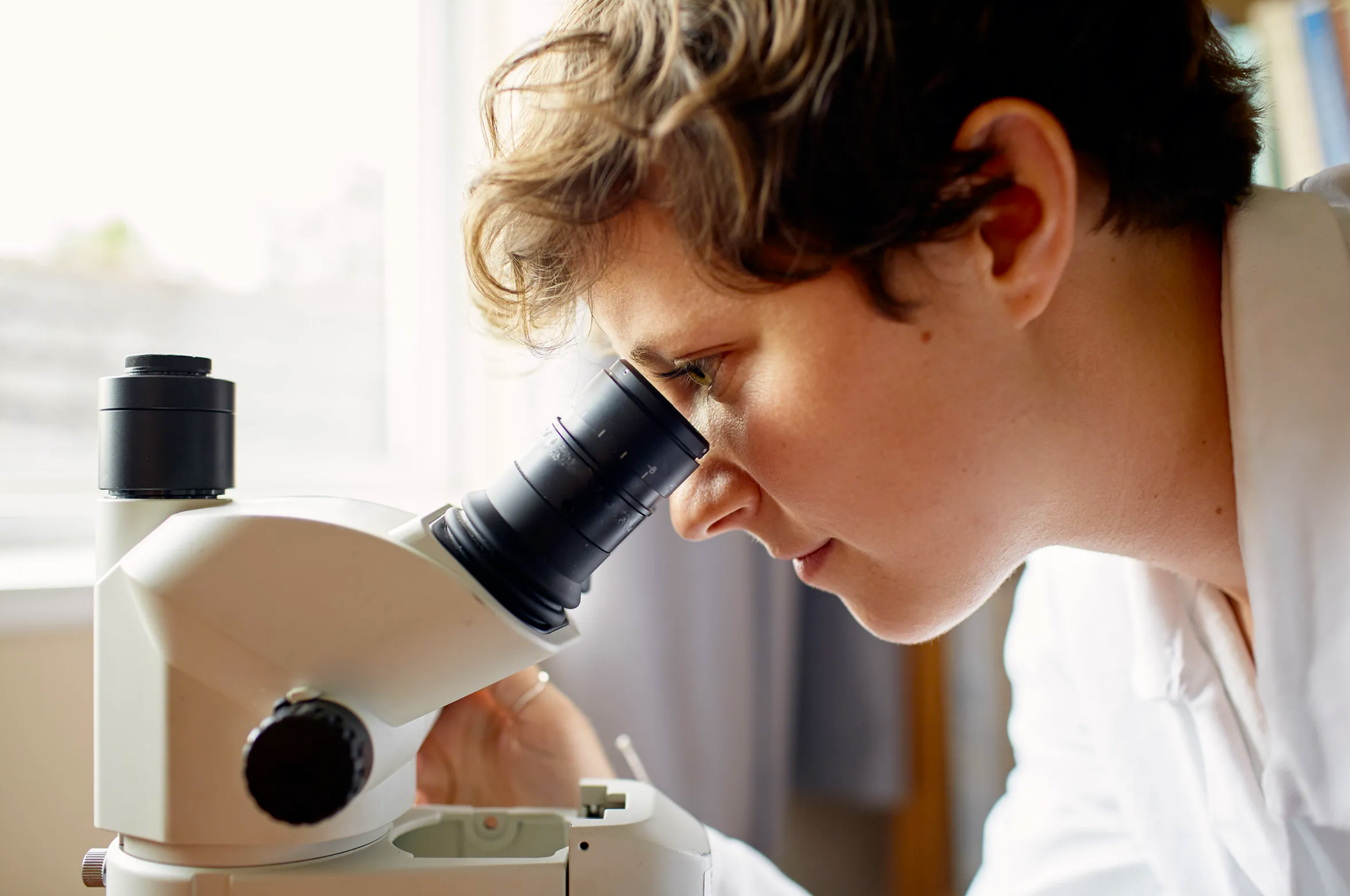 A scientist looking down a microscope